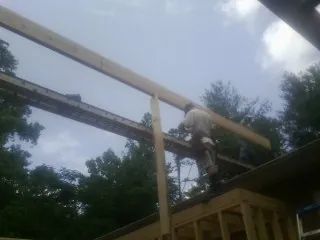 Carpenter setting a ridge beam over a new addition frame — Ice Dam Removal by Roofing Brothers in Cedar Rapids