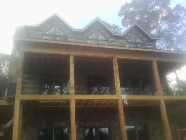 Dormers and porch framing on a large log home under construction — Roof Coating work by our crew in Cedar Rapids