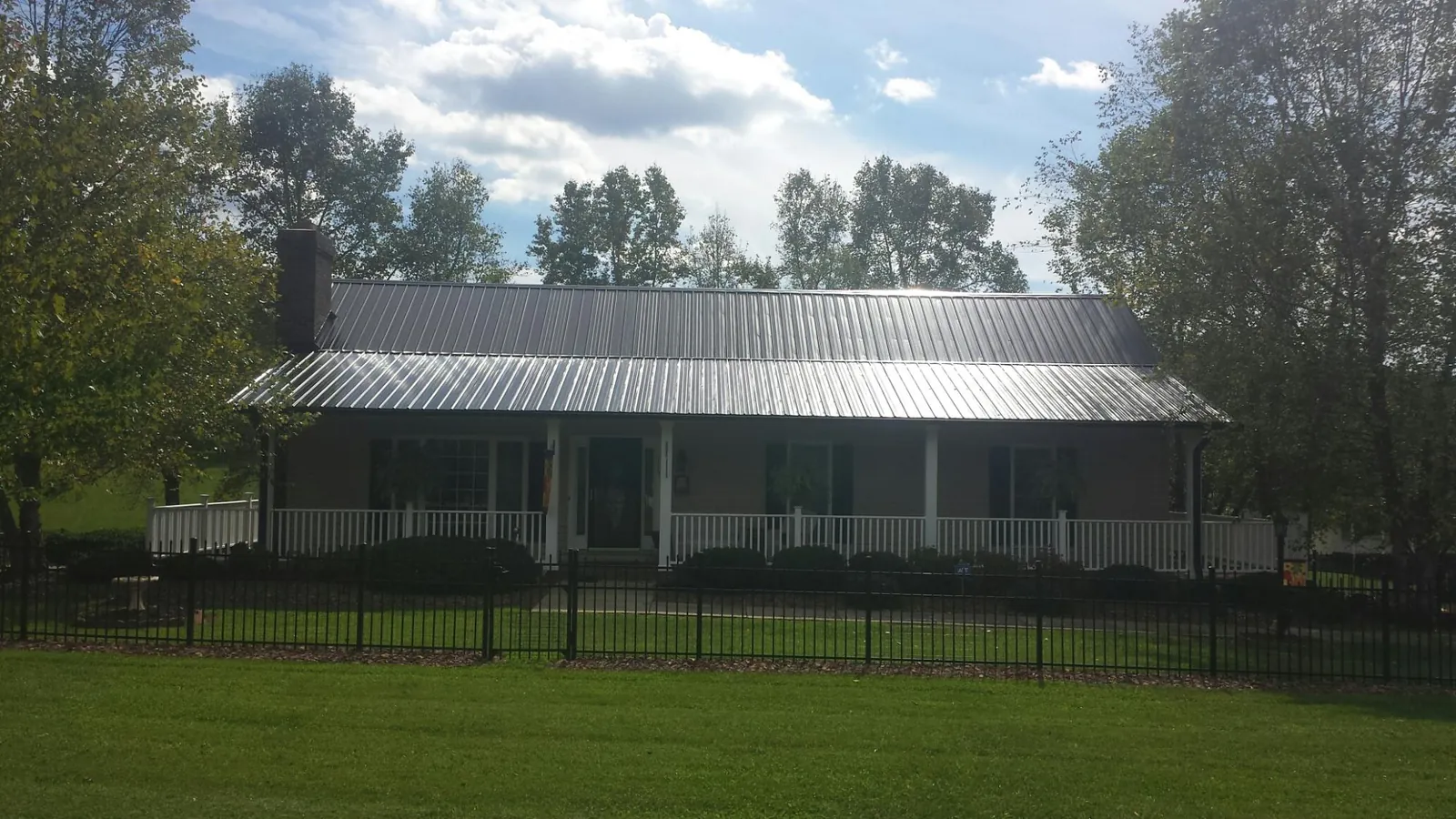 Gray metal roof on a brick ranch with a full width front porch — Gutter Guard Installation work by our crew in Cedar Rapids