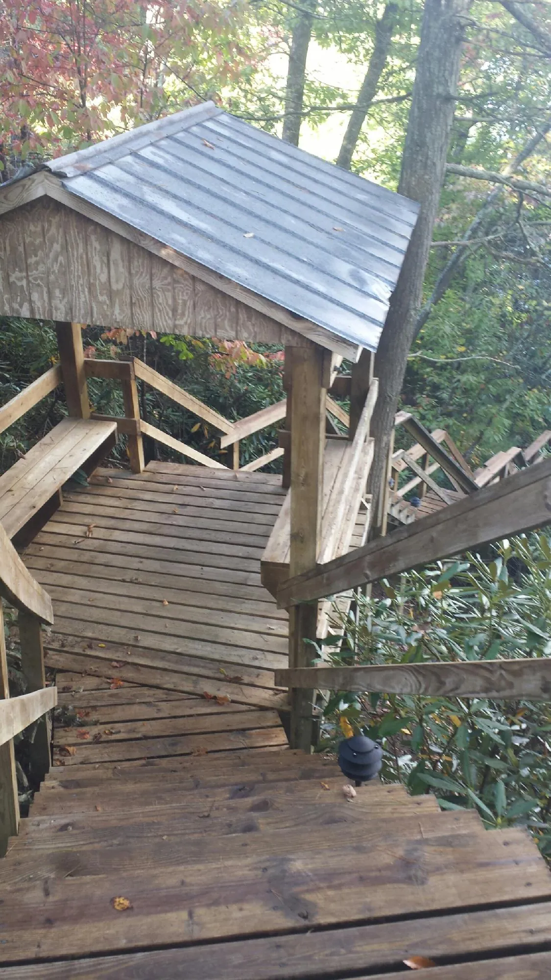 Metal roofed shelter over wooden steps on a wooded walkway — Skylight Repair & Installation work by our crew in Cedar Rapids