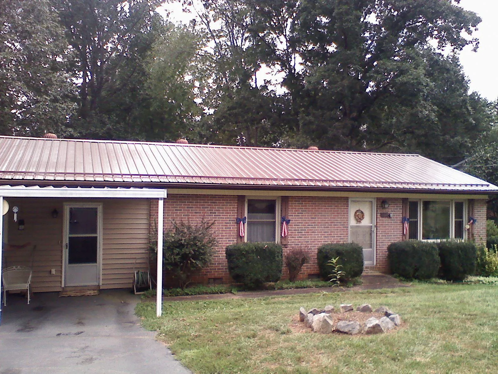 Bronze metal roof and carport on a brick ranch home — Roof Repair work by our crew in Cedar Rapids